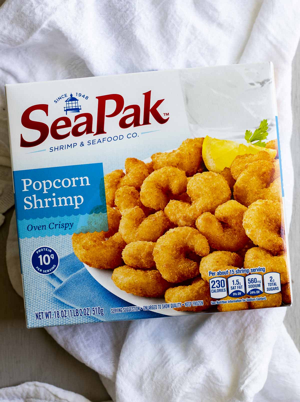 A package of frozen popcorn shrimp on a white cloth.