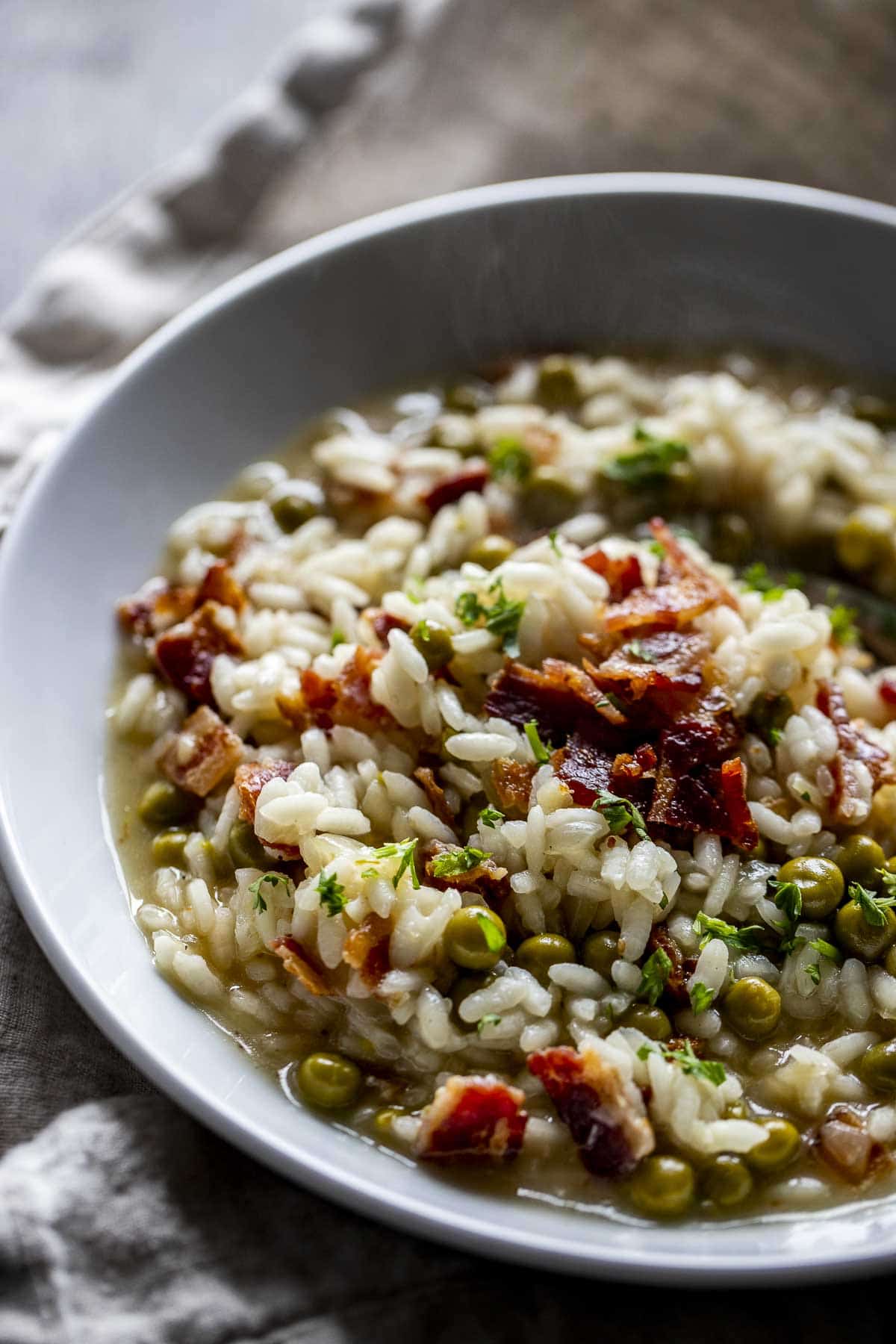 45 degree view of pea and bacon risotto in a bowl.