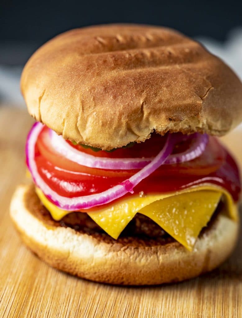 Close up side view of a sous vide hamburger on a bun with toppings.