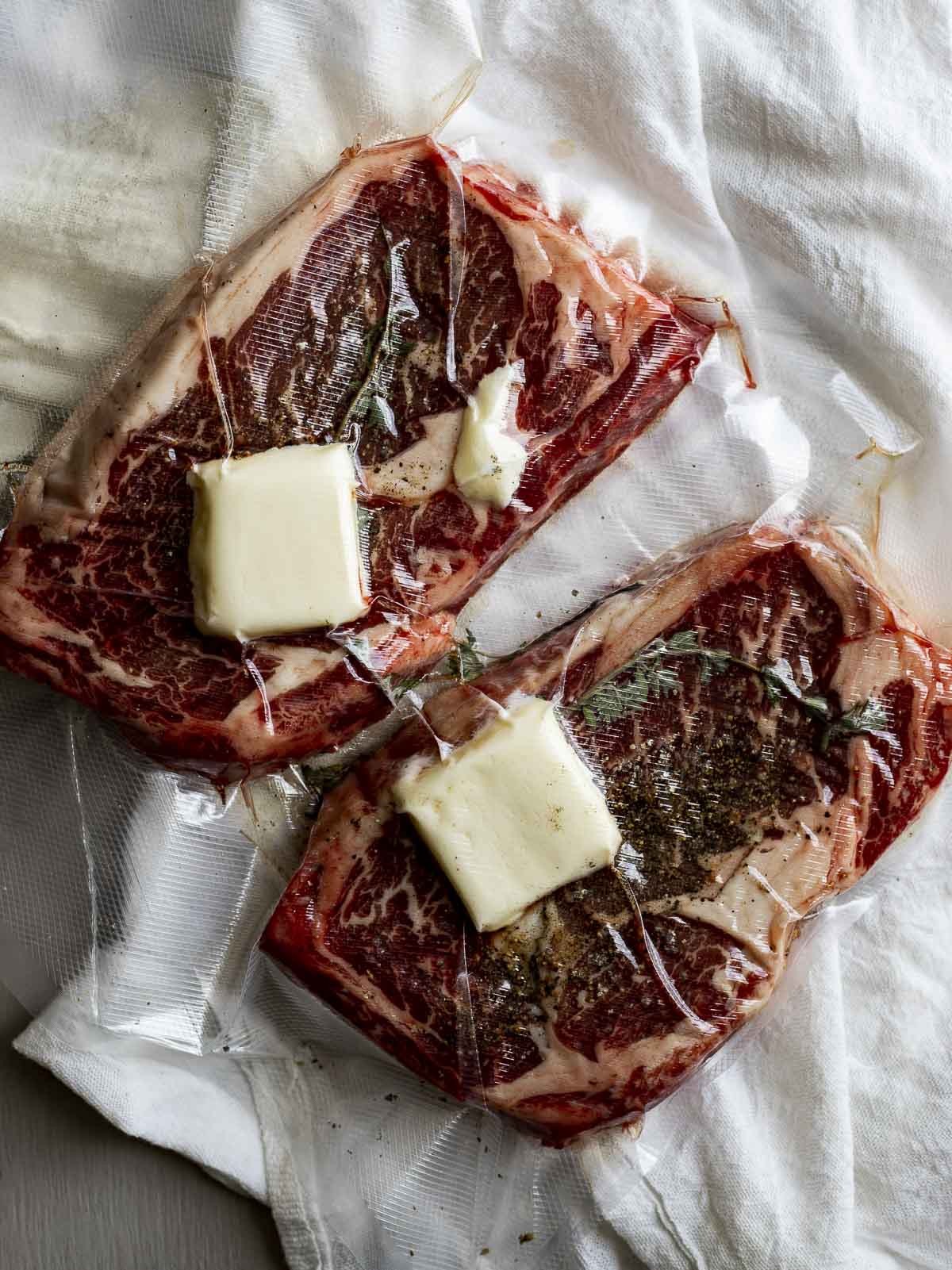 Two ribeye steaks vacuum sealed in a bag with butter, garlic and herbs.