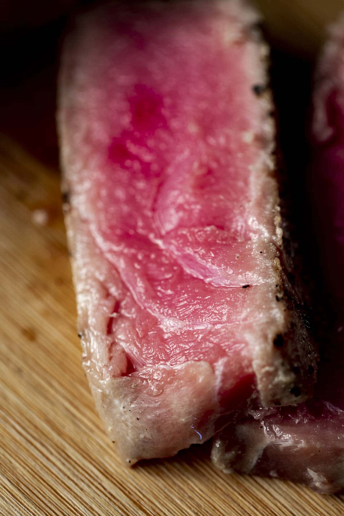 Close up view of a slice of tuna showing the rare, pink middle and outer crust.