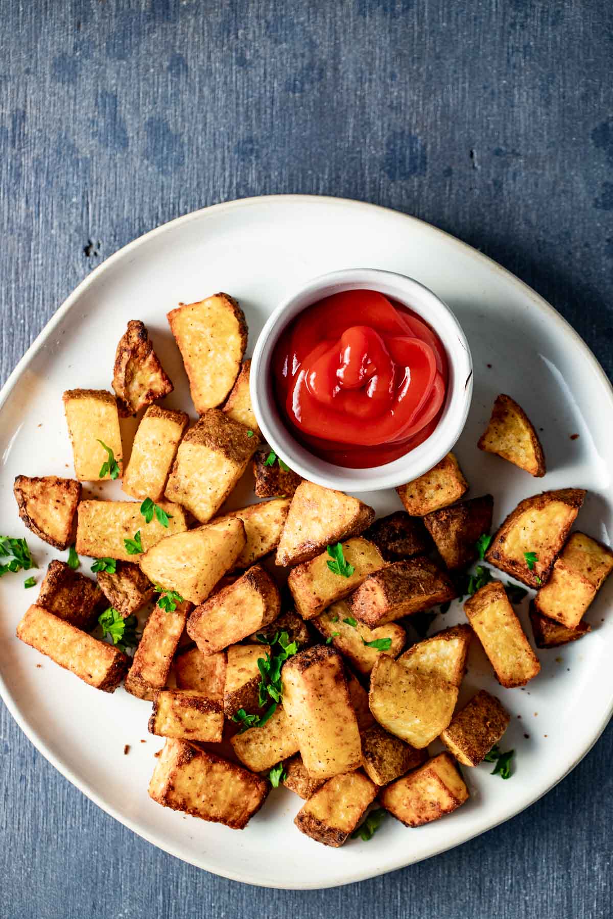 Overhead view of air fryer breakfast potatoes on a plate with ketchup.