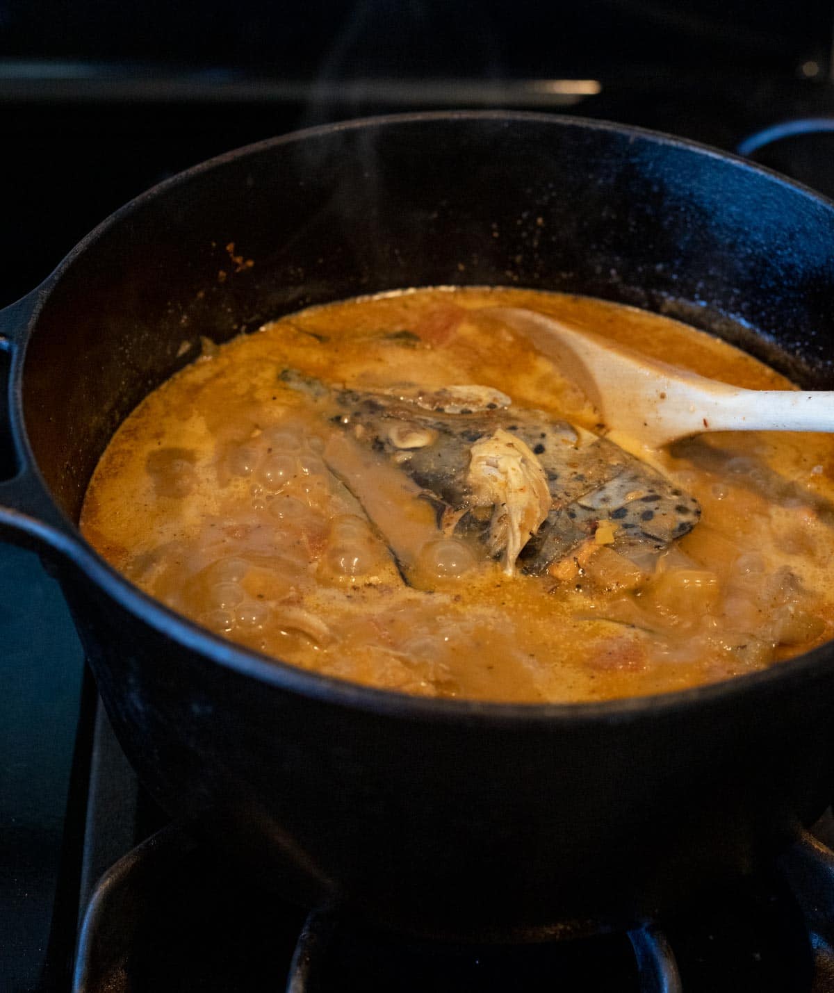 Fish head curry simmering in a Dutch oven.