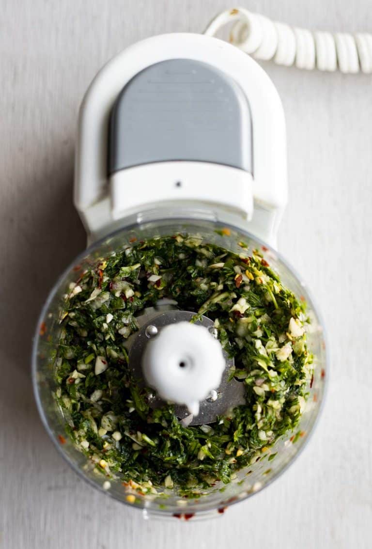 Overhead view of mint chimichurri processed together in a food processor.