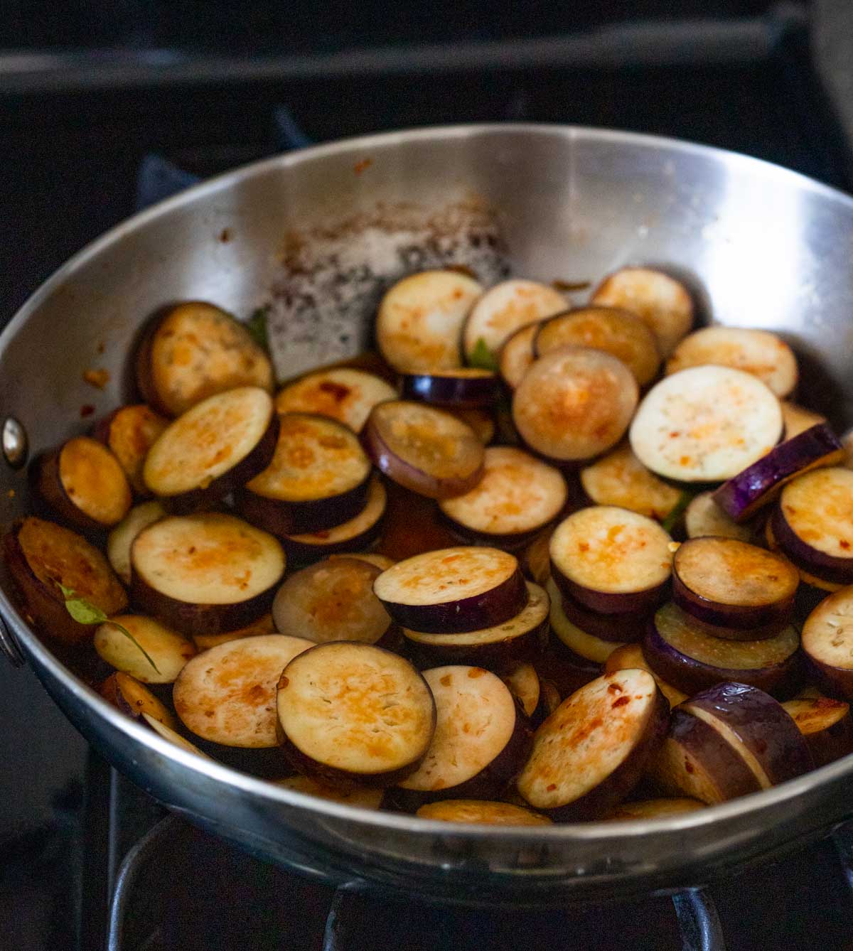 Slices of eggplant cooking in a skillet.