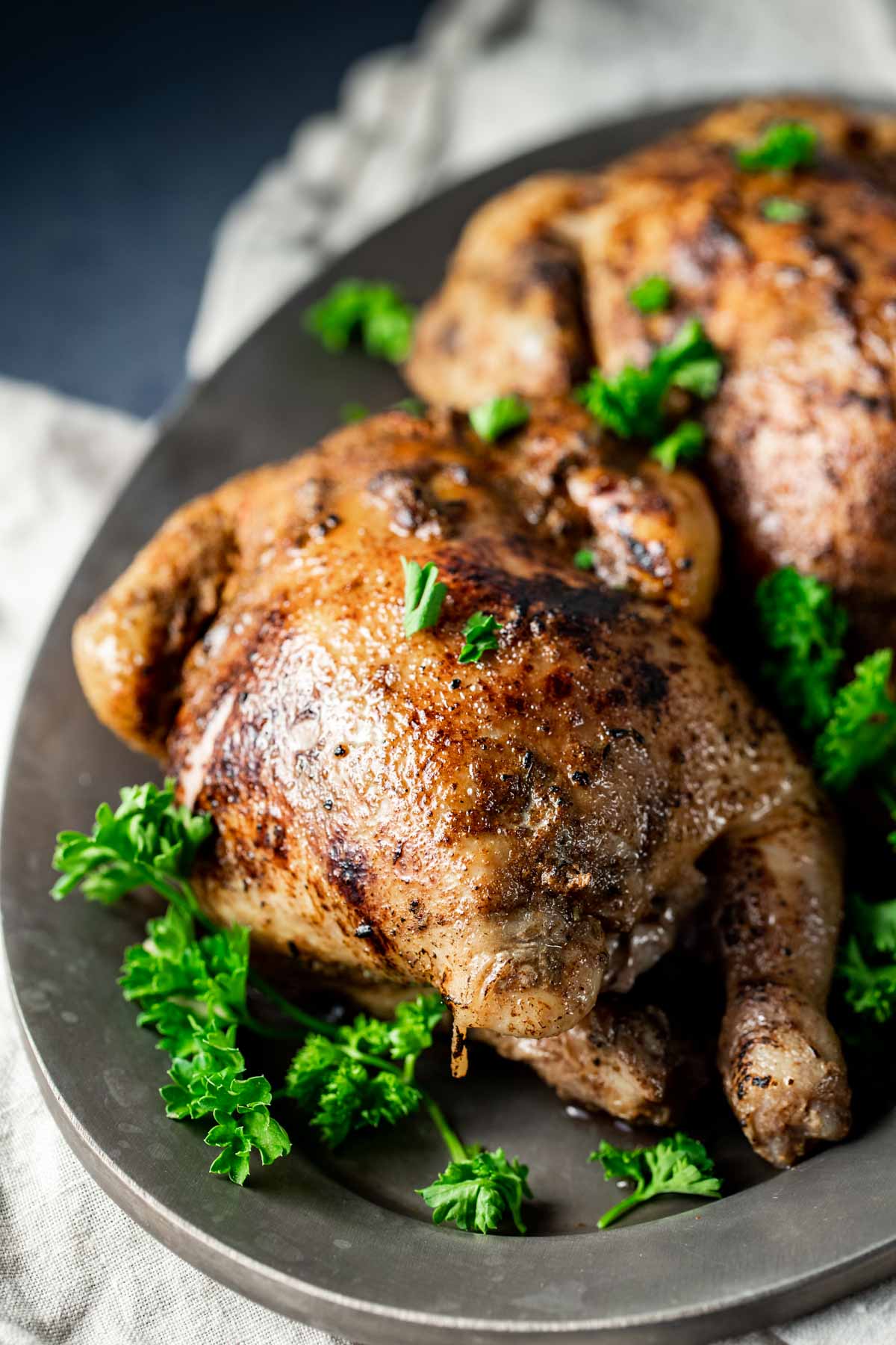 Cornish hens served on a platter with green herbs.