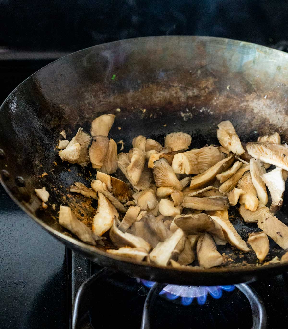Mushrooms cooking in a wok on the stovetop.