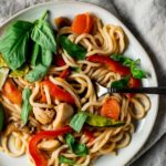 Overhead view of tom yum noodles on a plate with a fork.