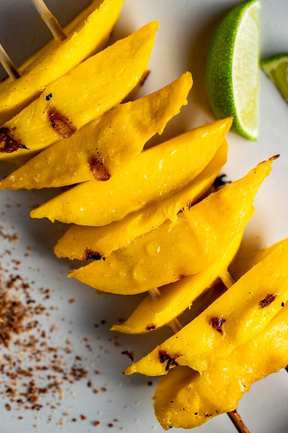 Close up view of grilled mango slices on a white plate.