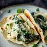 Side view of rajas con crema in tortillas on a plate.