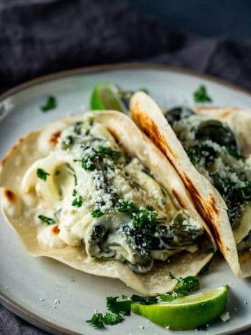Side view of rajas con crema in tortillas on a plate.