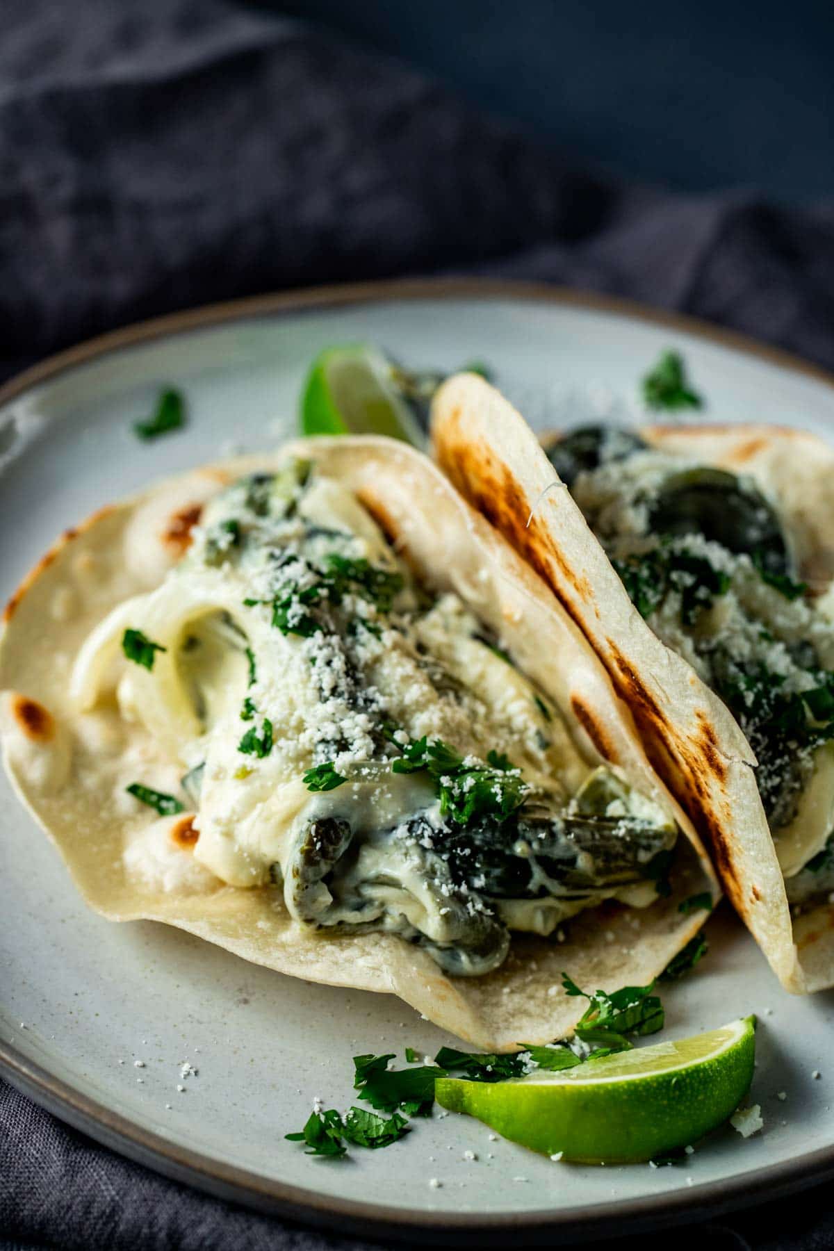 Side view of rajas con crema in tortillas on a plate.