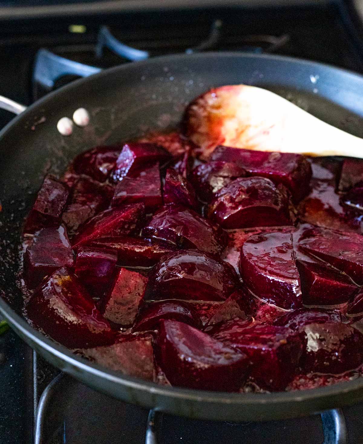 Beets with glaze being cooked in a skillet on the stovetop.