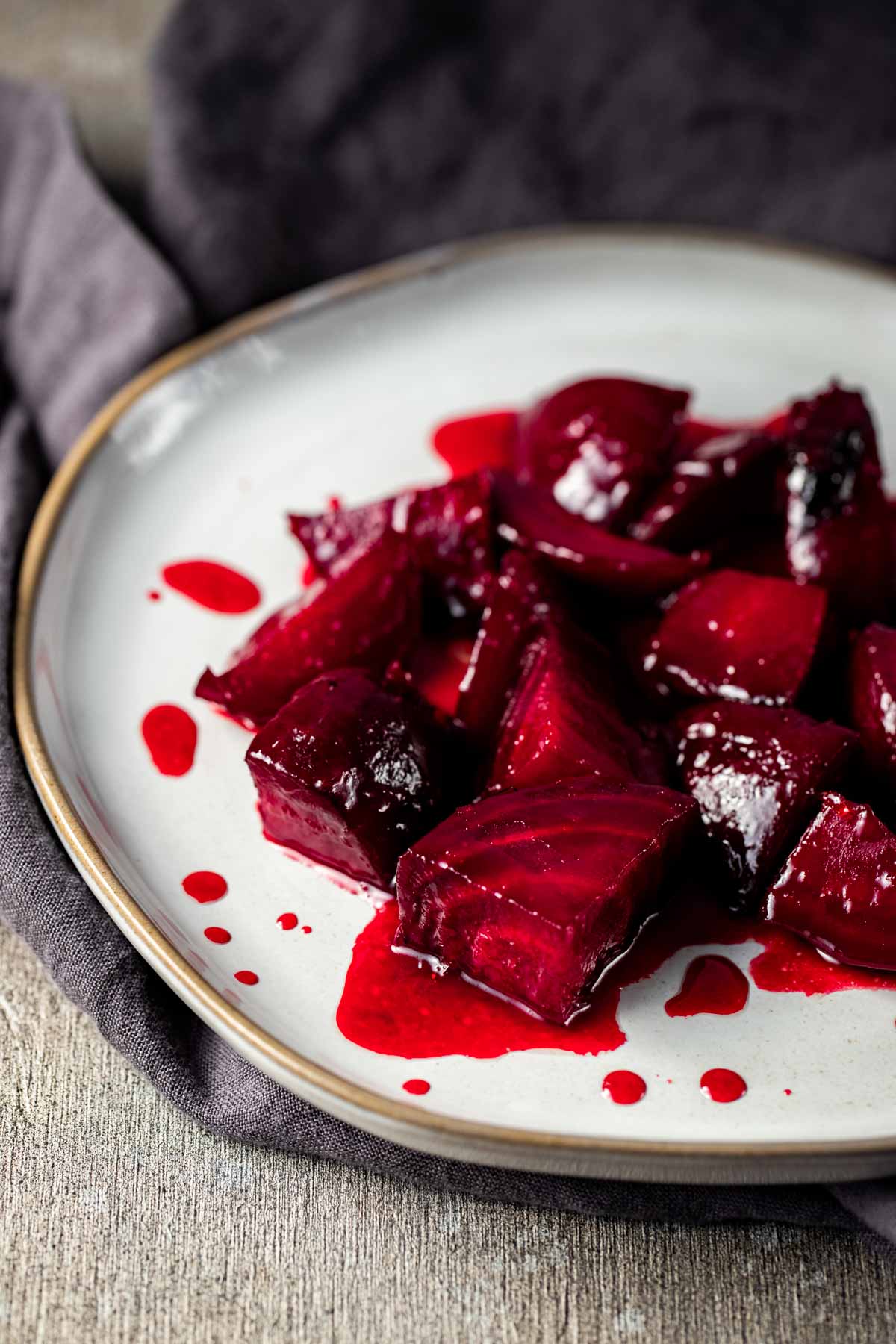 Side view of candied beets served on a white plate.