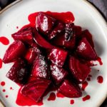 Overhead view of candied beets served on a white plate.