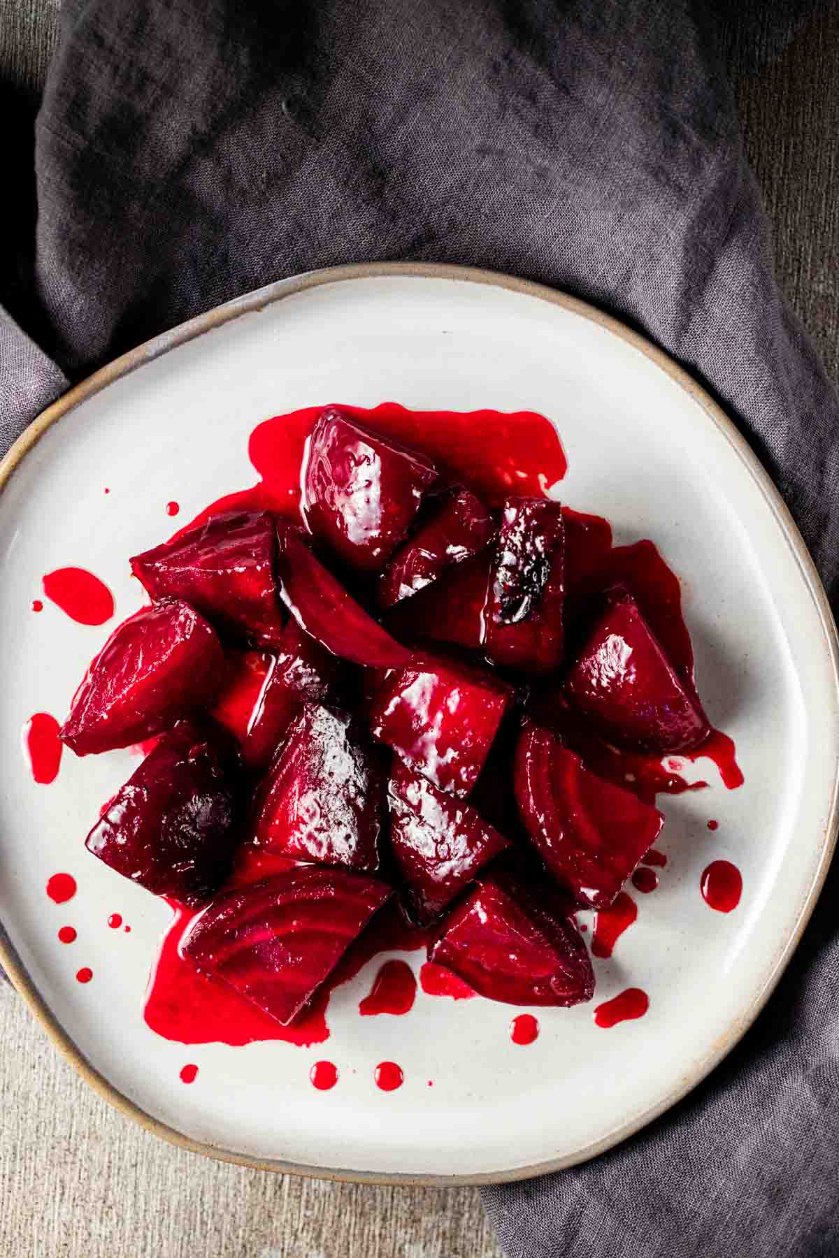 Overhead view of beet pieces with orange glaze on a white plate.