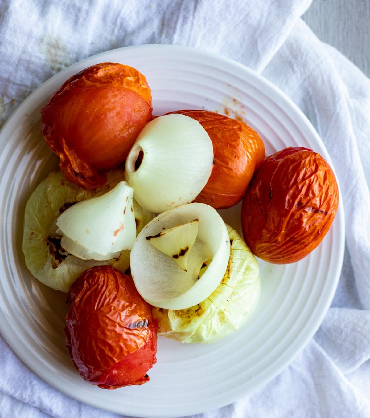 Roasted tomatoes and onions on a white plate.