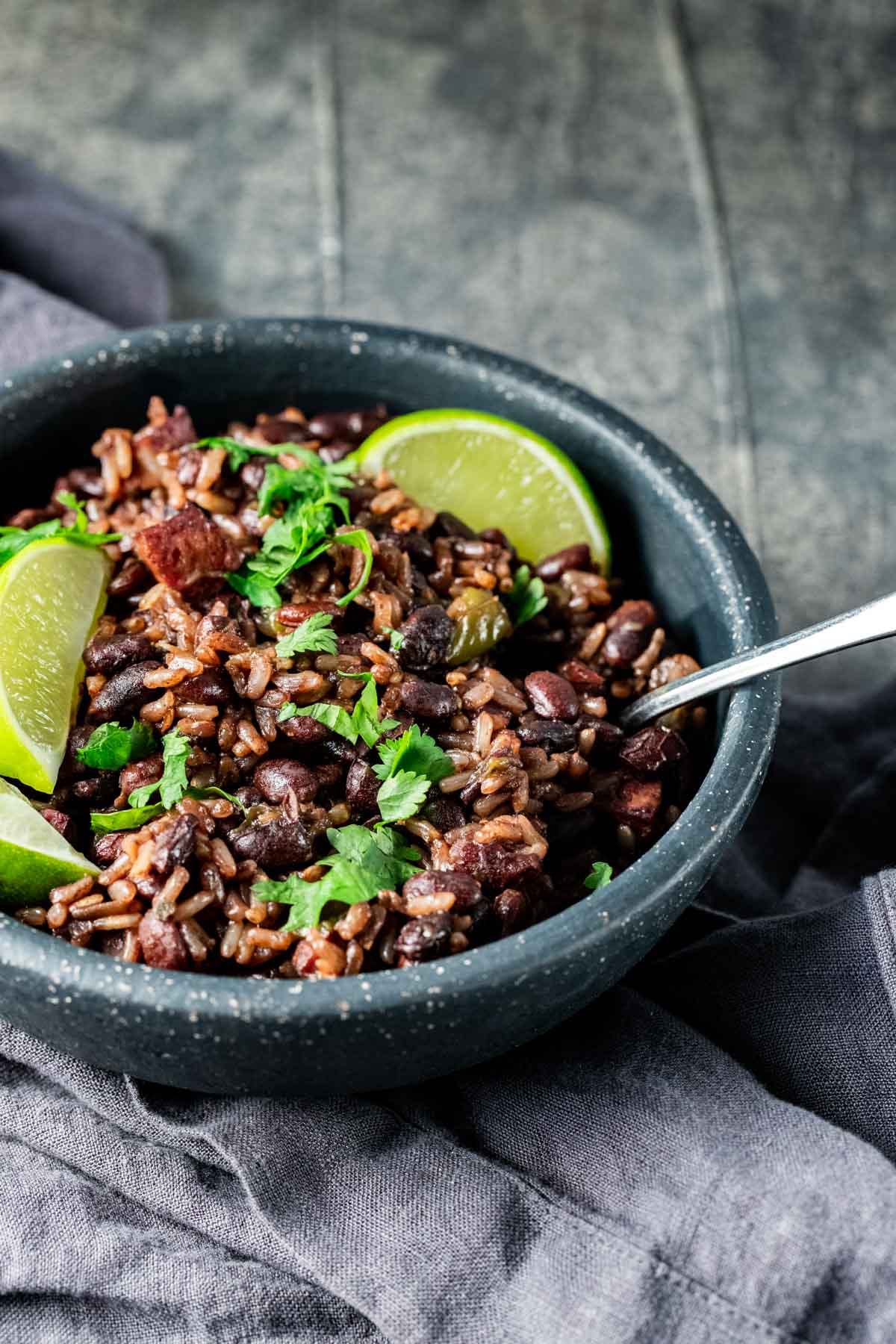 Side view of black beans and rice in a bowl with a spoon inserted into it.