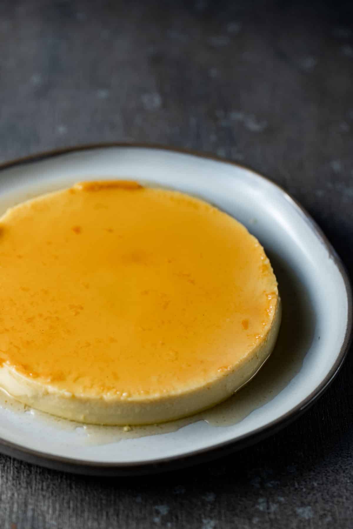 Side view of baked flan on a white plate.