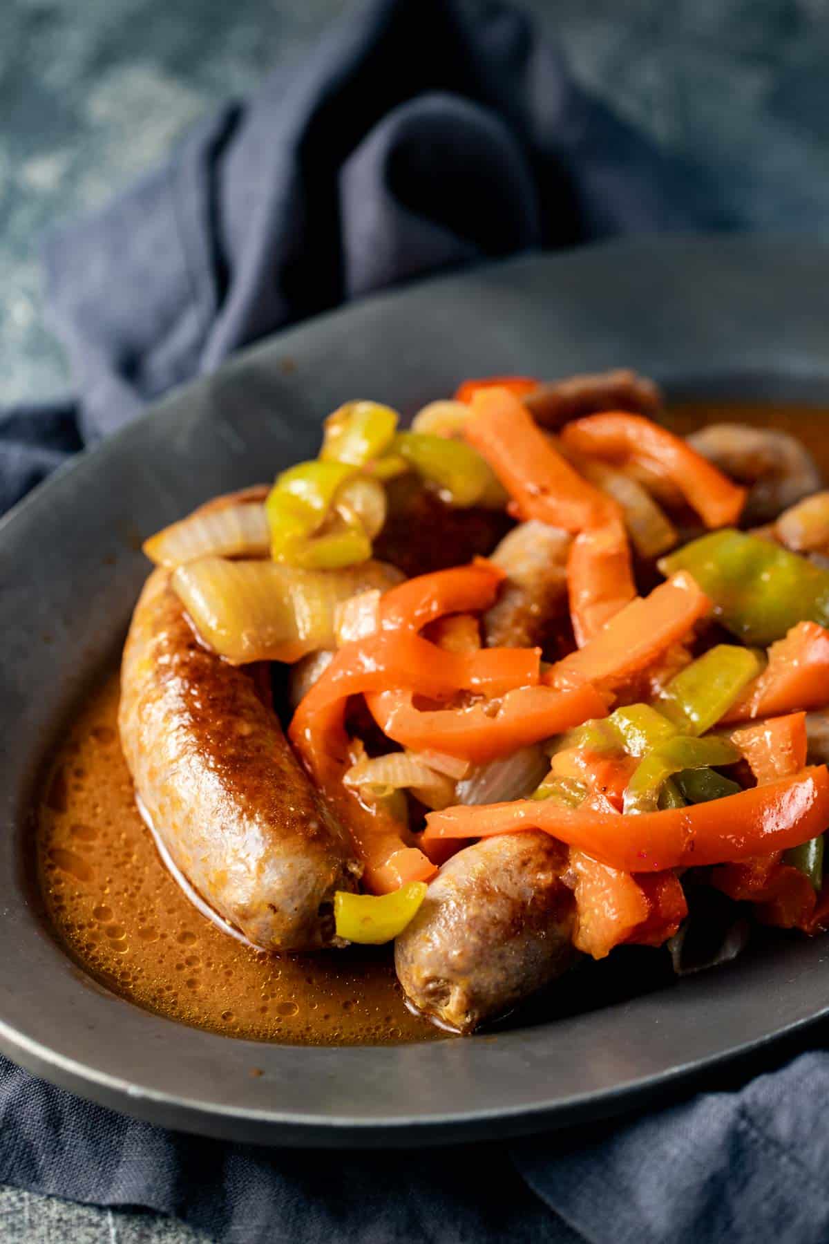 Side view of sausage and peppers served on an oval platter.