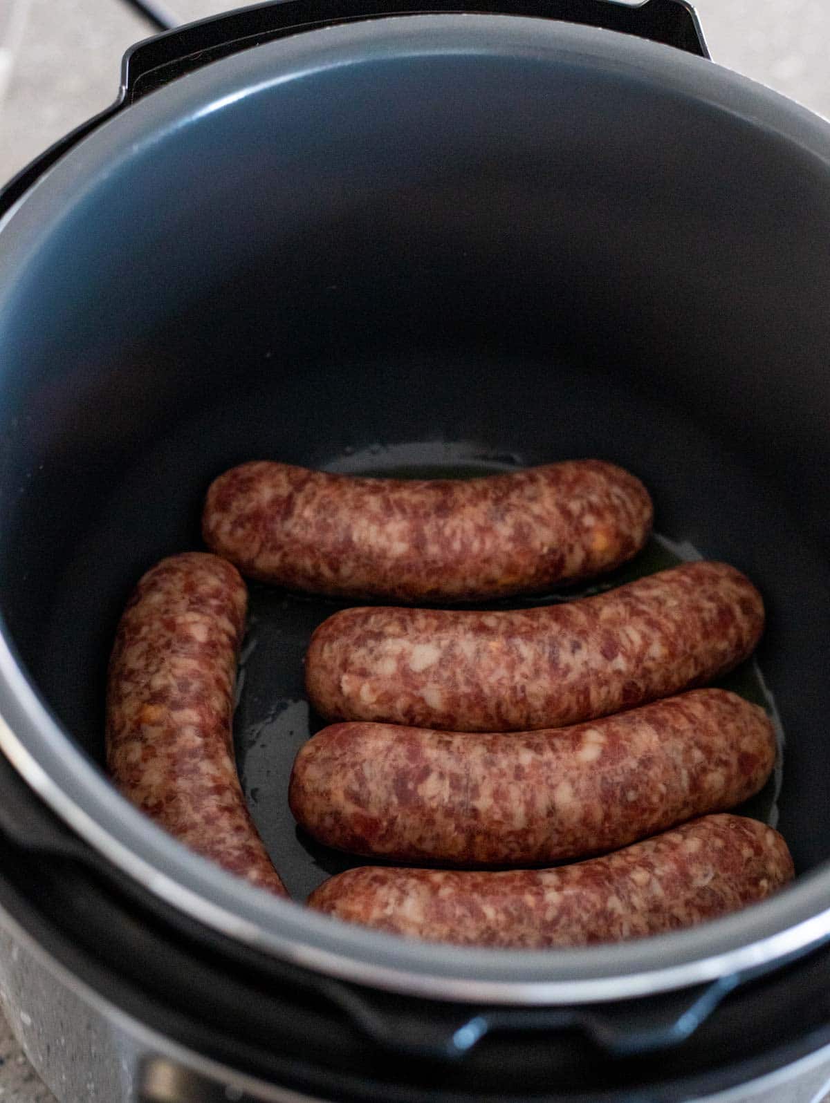 Raw sausages being browned in the Instant Pot insert.