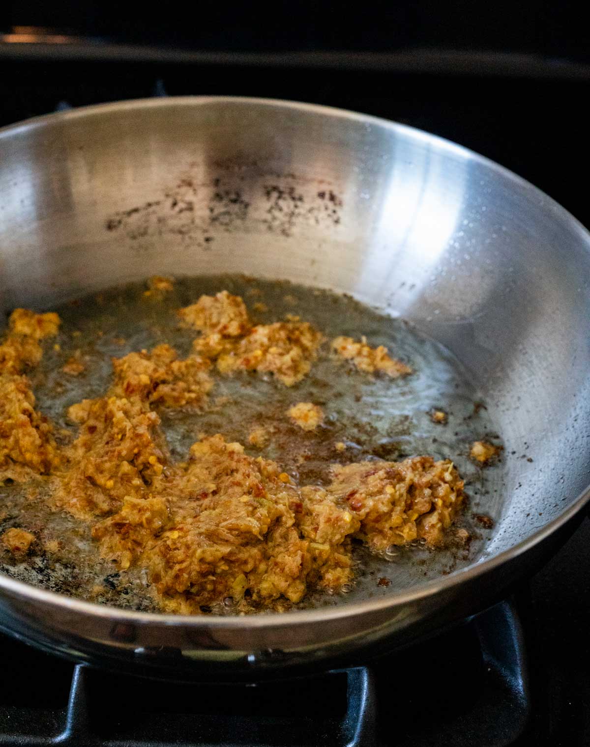 Chili paste being fried in a skillet.