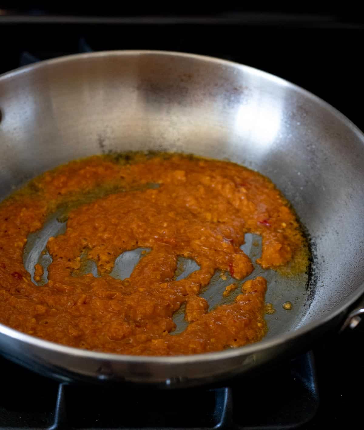 Spice paste cooking in a high-sided skillet.