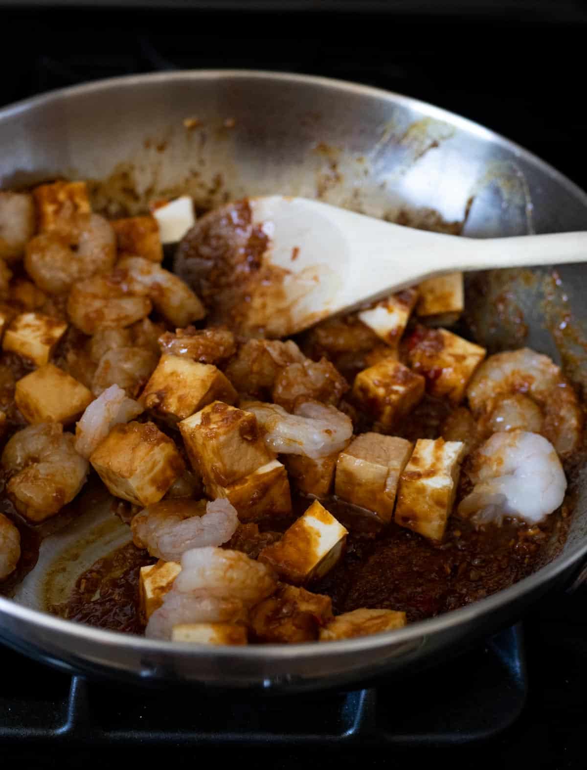 Tofu and shrimp added to the spice paste in the skillet.