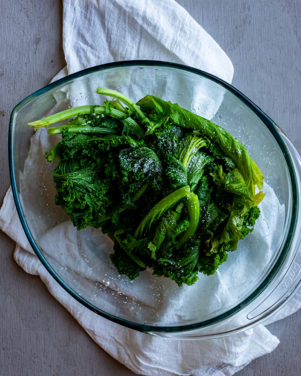 Blanched mustard greens resting in a large glass bowl.