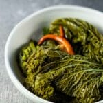 Side view of pickled mustard greens served in a white bowl.