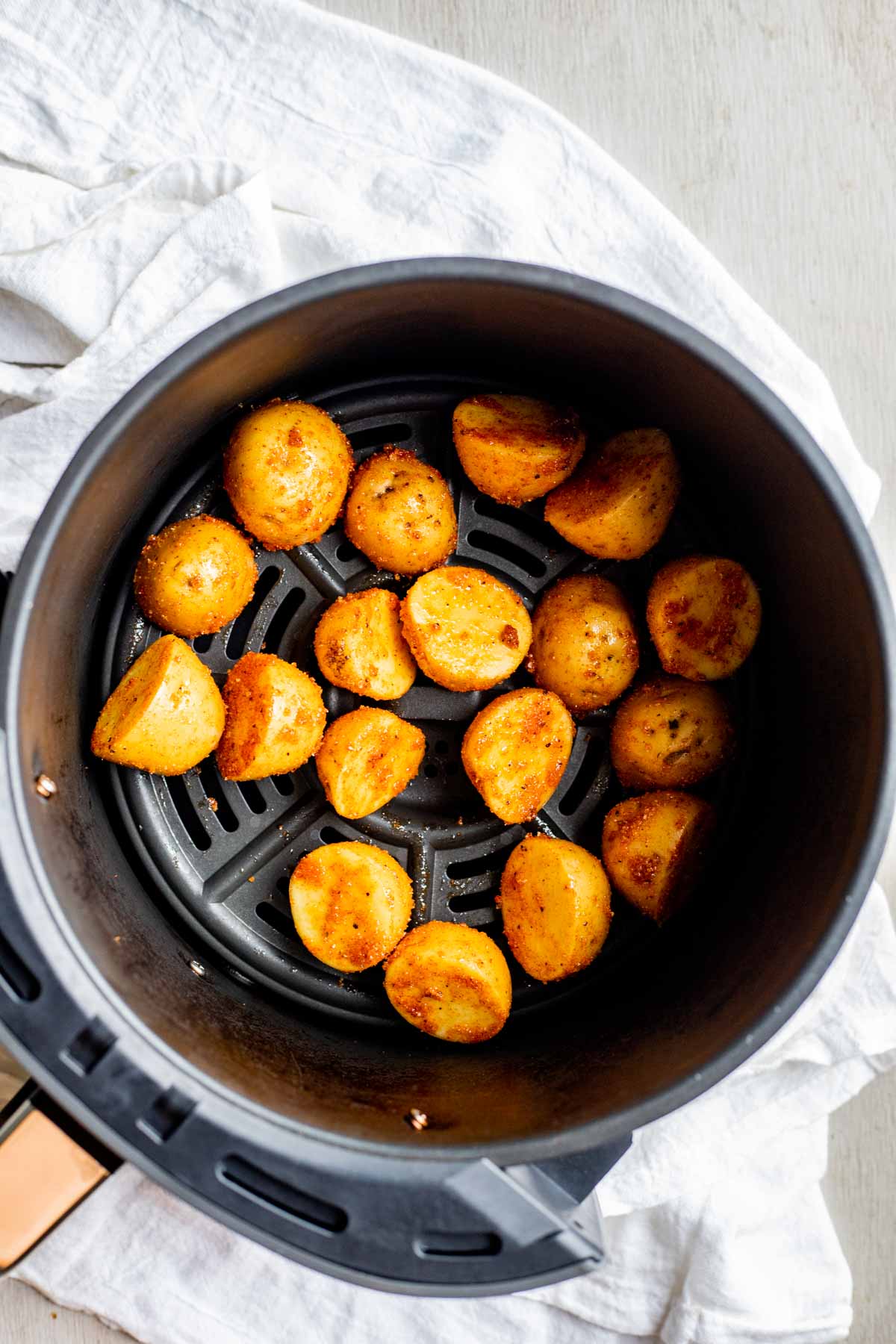 Seasoned baby potatoes in an air fryer basket.