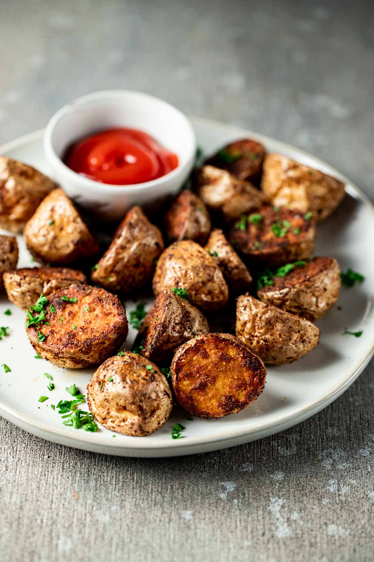 Crispy air fryer baby potatoes on a plate with ketchup on the side.