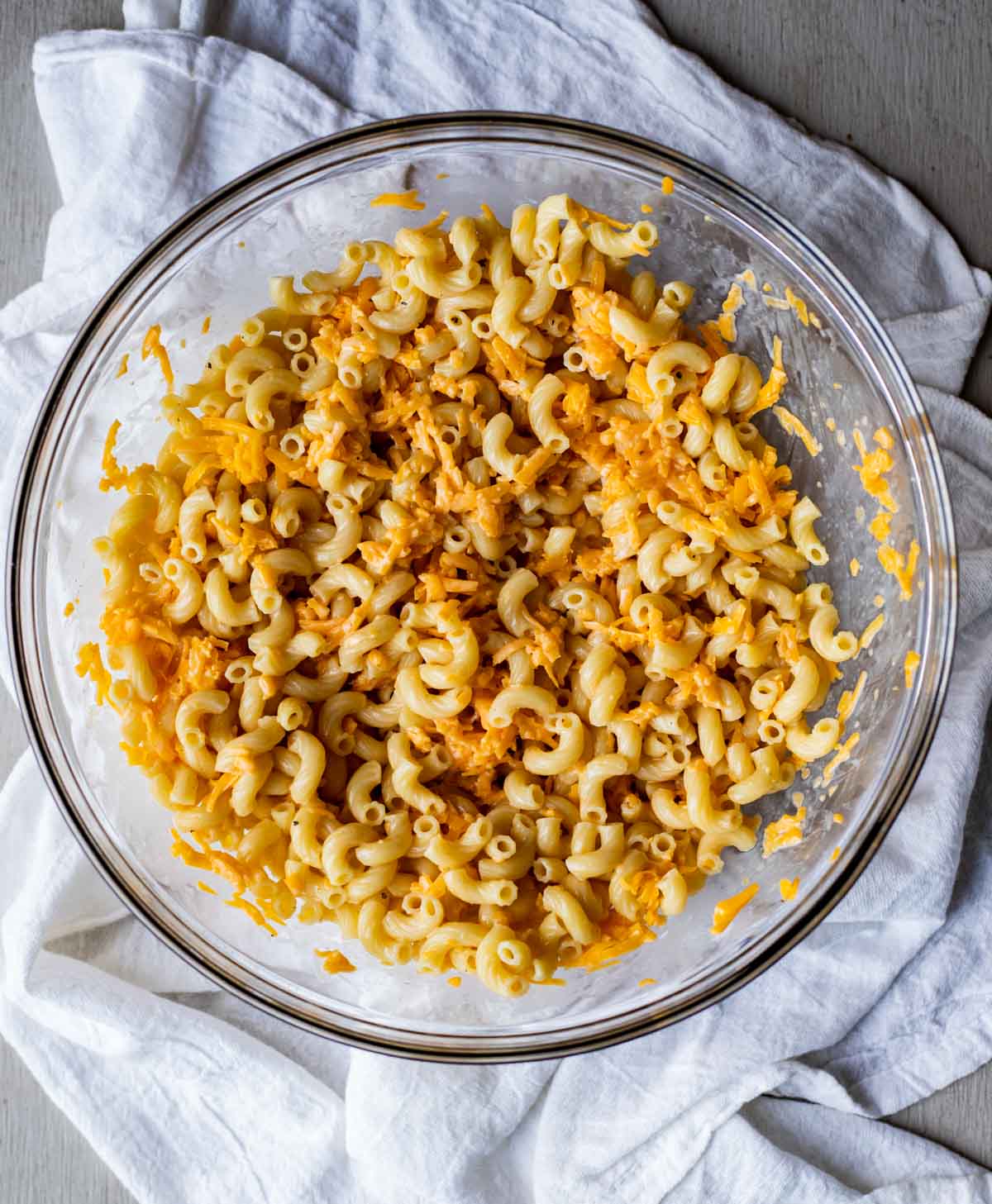 Mac and cheese ingredients mixed together in a large glass bowl.