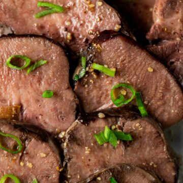 Sliced beef tongue topped with chopped green onion.