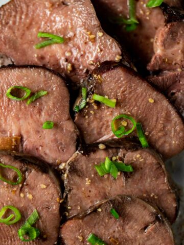 Sliced beef tongue topped with chopped green onion.
