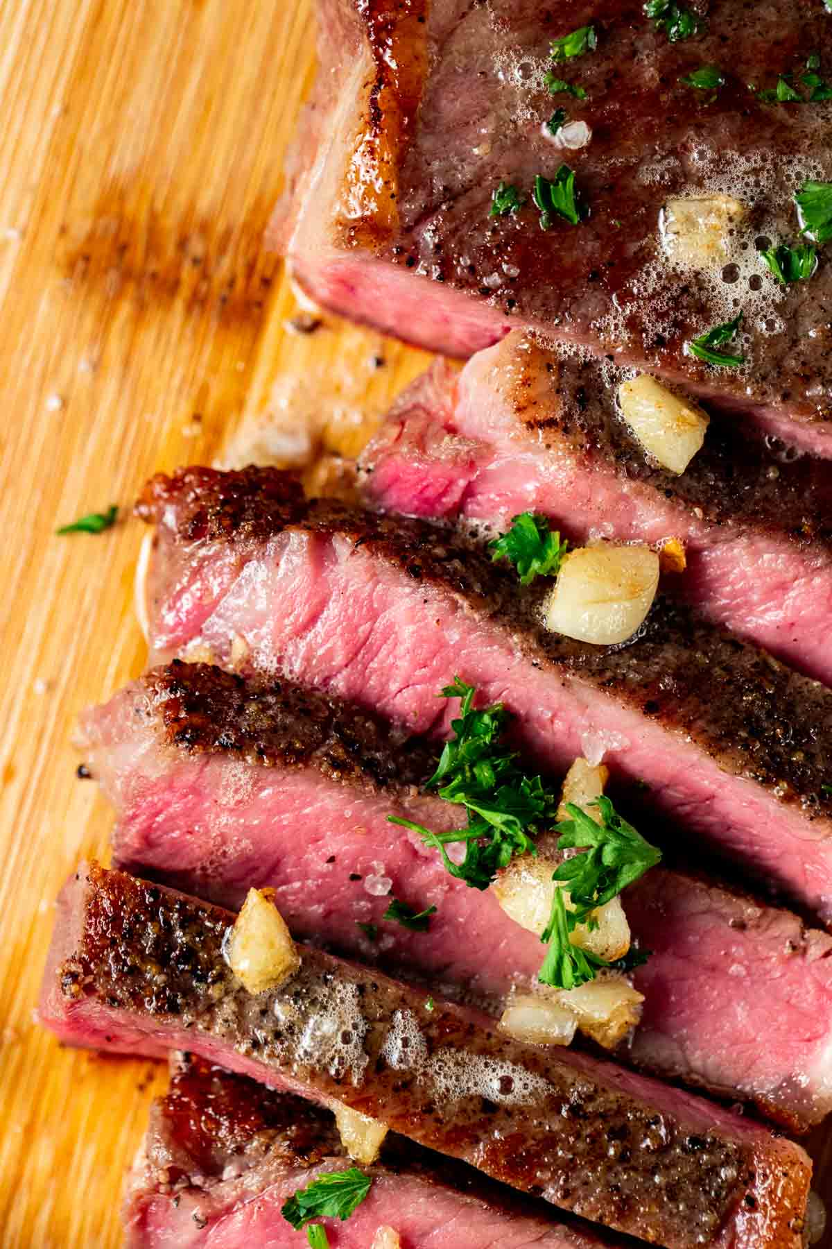 Medium rare steak cut into slices and topped with chopped herbs.