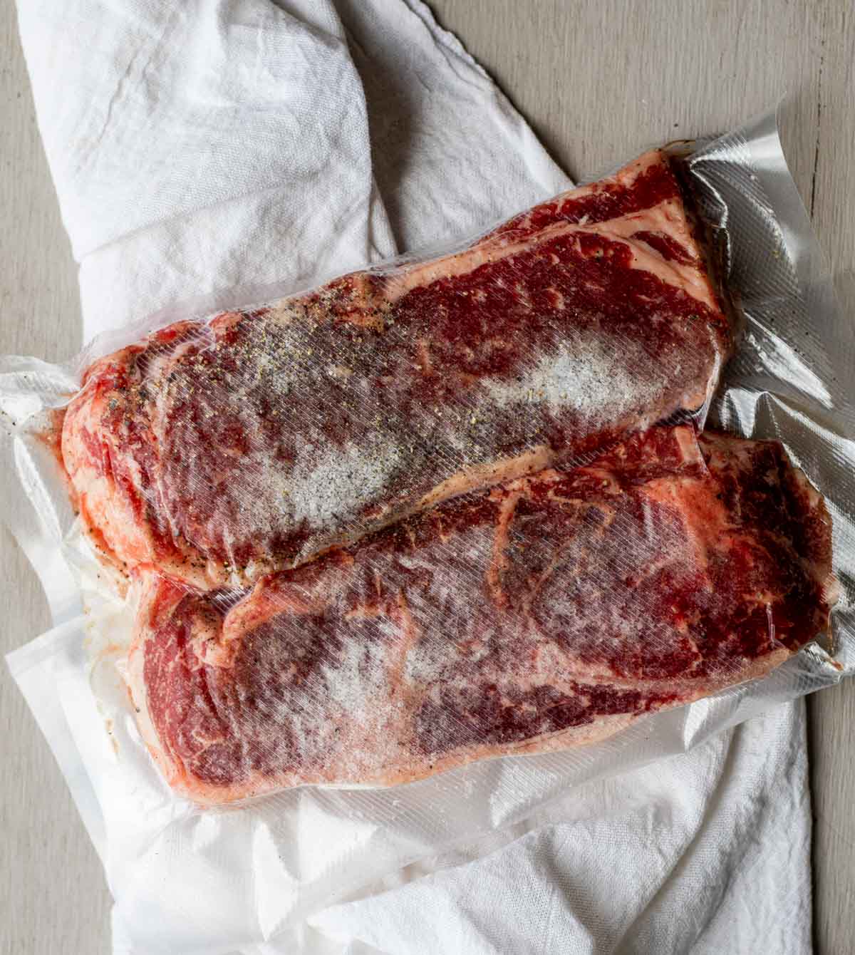 Two frozen steaks vacuum sealed in a bag.
