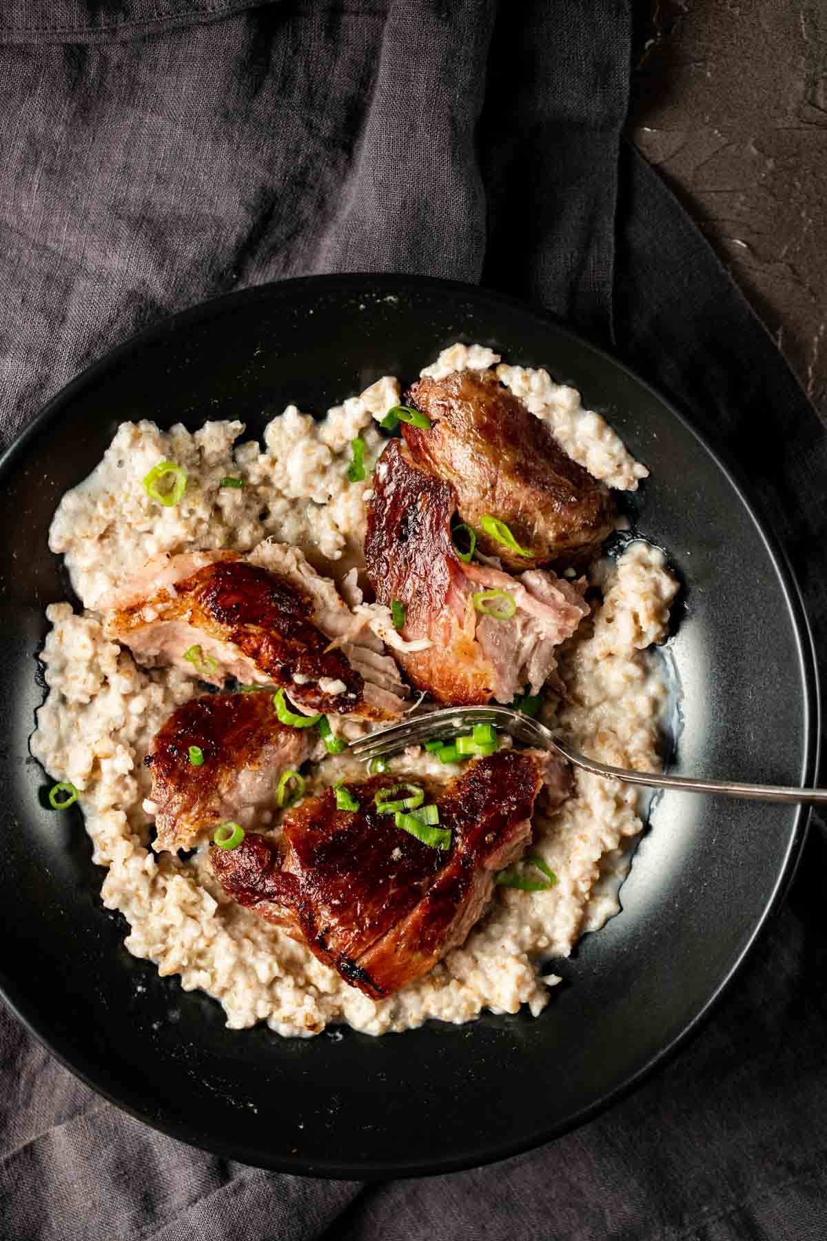 Overhead view of pork shoulder and rice on a plate with a fork.
