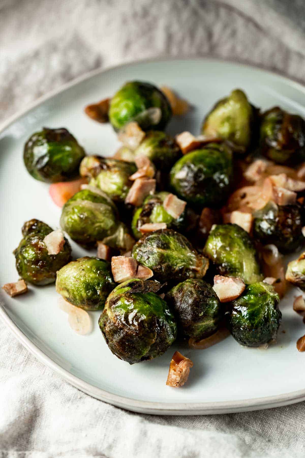 Side view of air fryer frozen Brussels sprouts on a white plate.