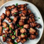 pieces of pork belly on a white plate cut into small pieces
