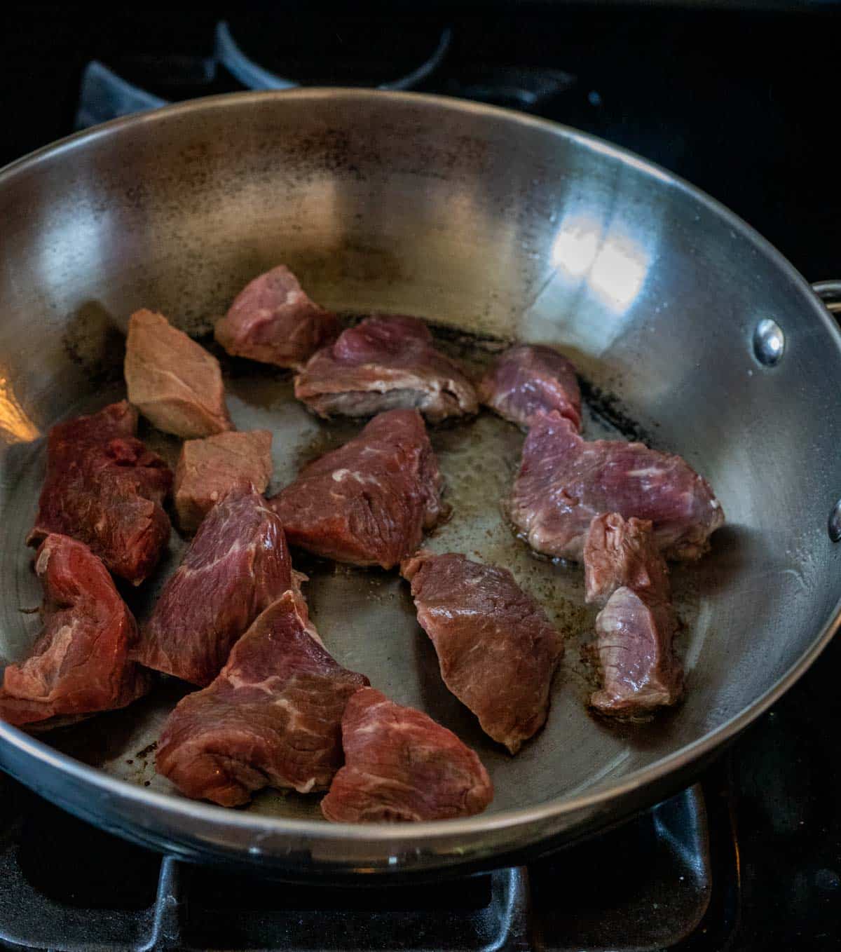 Beef browning in a skillet on the stovetop.