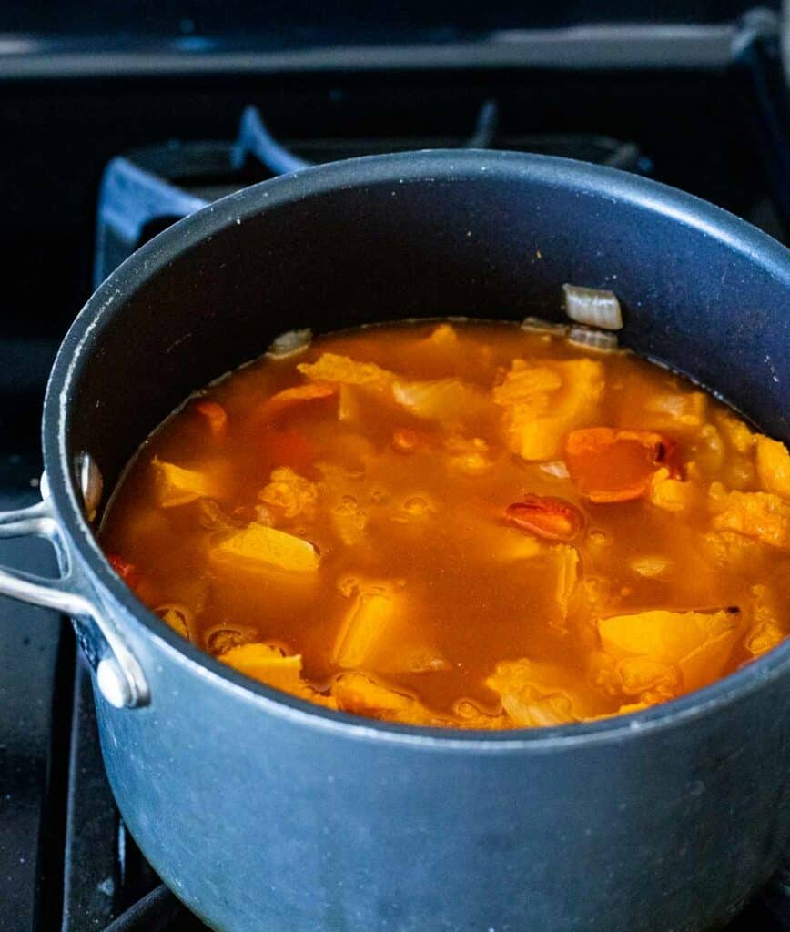 orang colored vegetables simmering in liquid in a pot