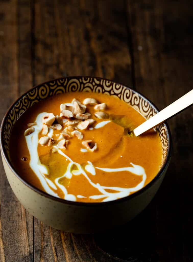 a bowl of butternut squash and red pepper soup on a wood surface