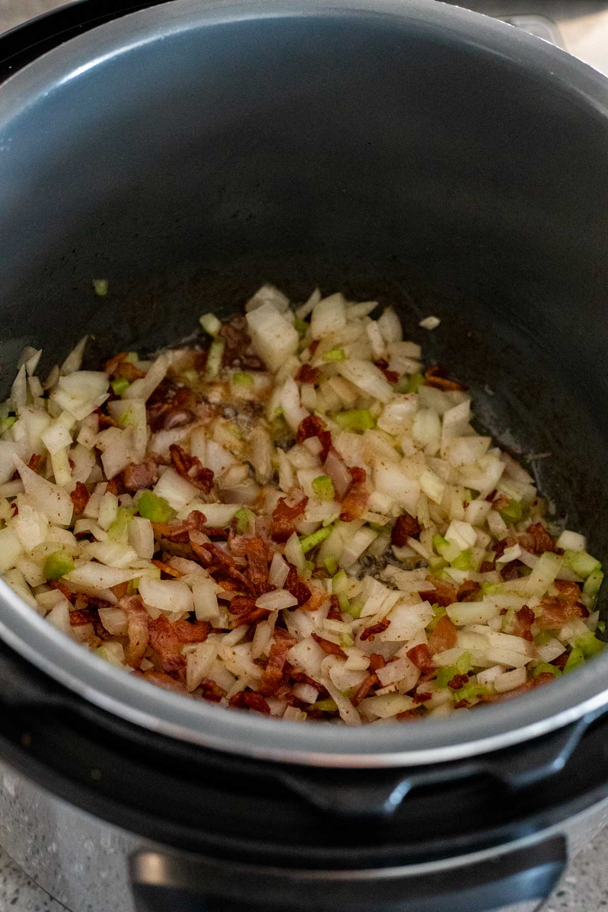 Onion, celery and bacon in the Instant Pot insert.