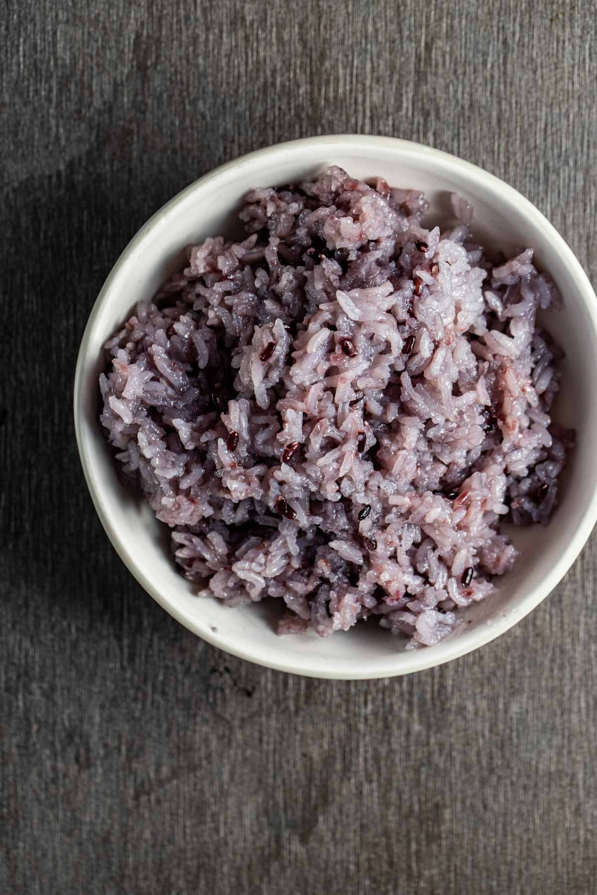 Overhead view of Korean purple rice in a white bowl.