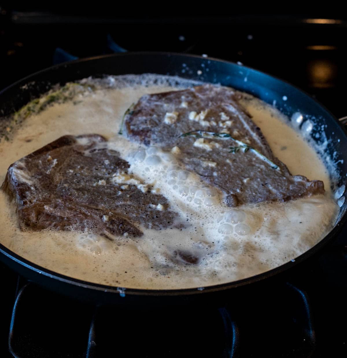 Milk steak being cooked in a skillet.