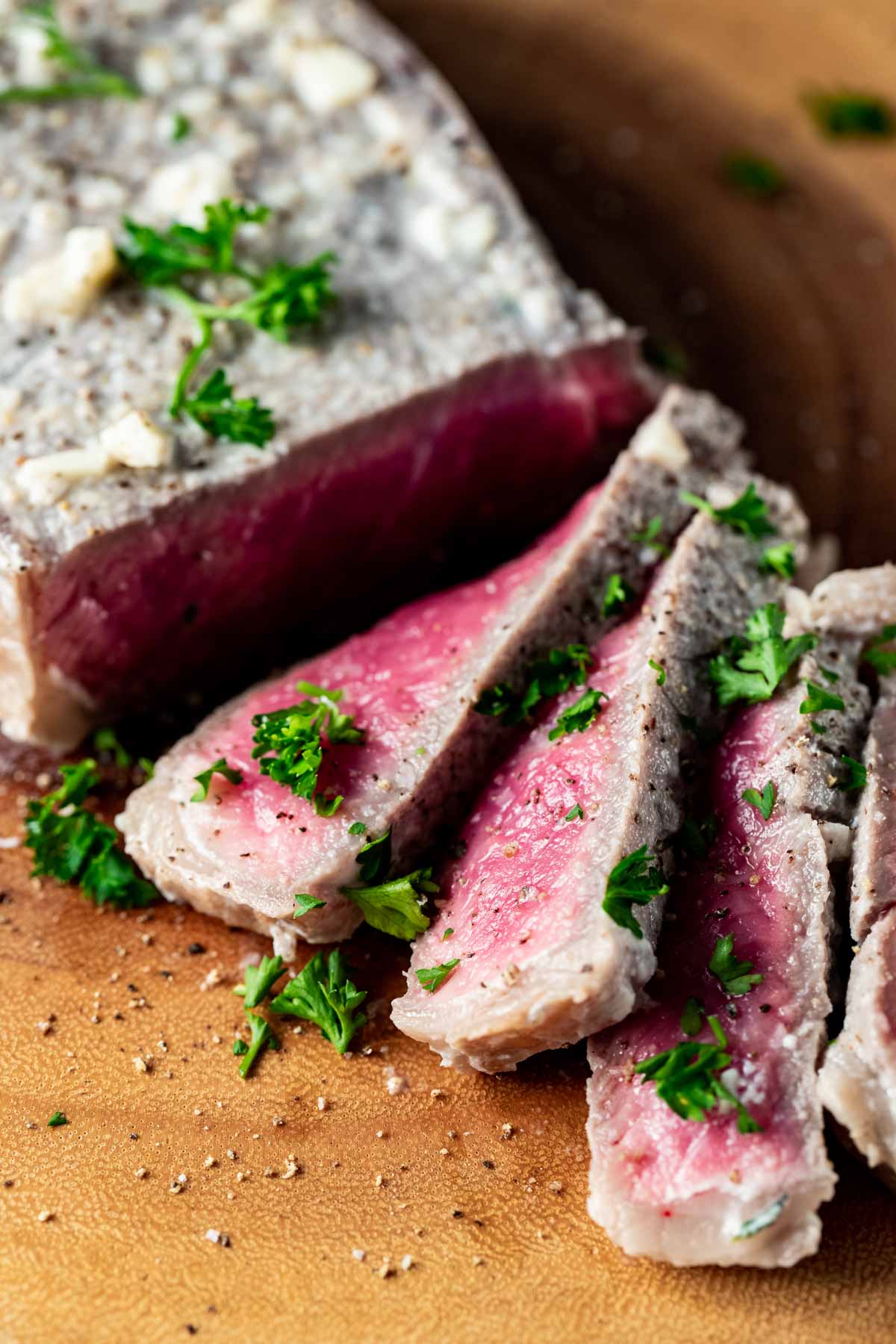 Close up view of milk steak cut into thin slices and garnished with chopped herbs.