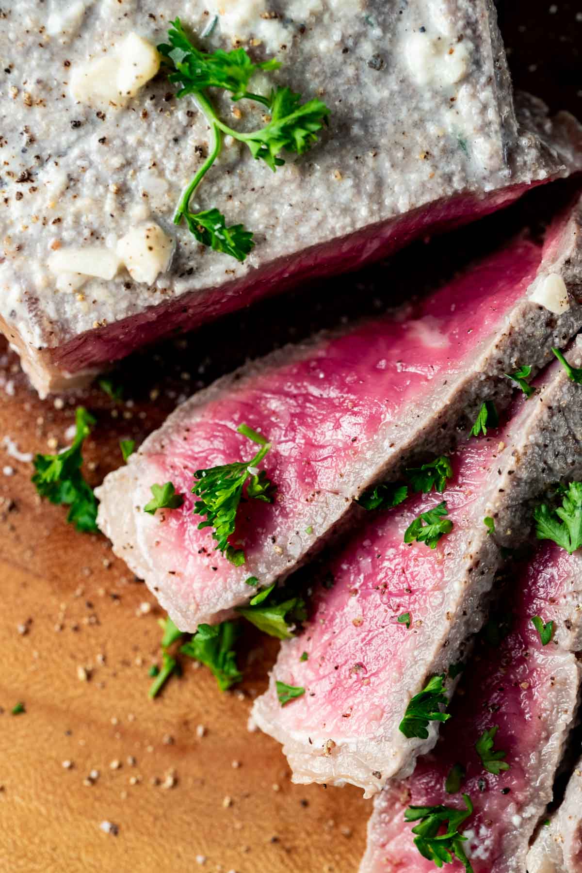 Close up view of sliced milk steak with herbs on top.