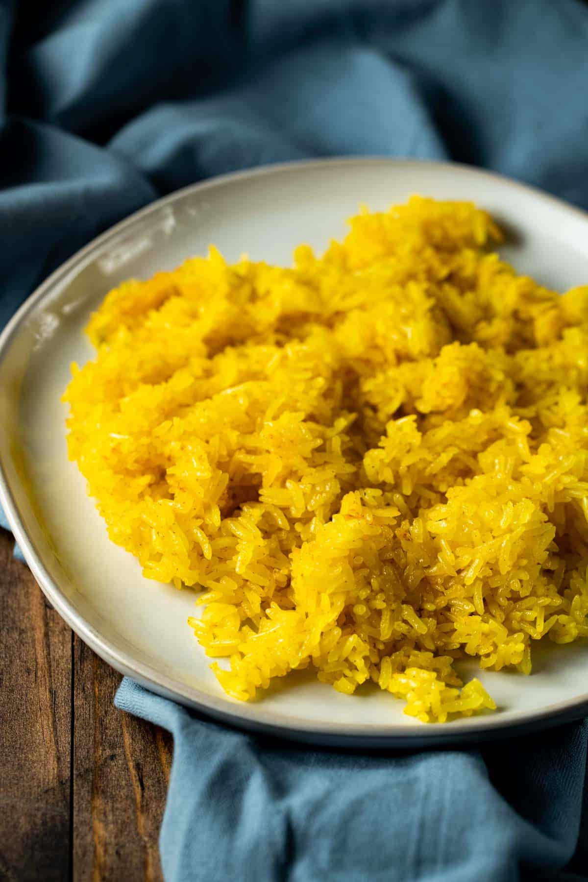 Side view of turmeric rice on a white plate.
