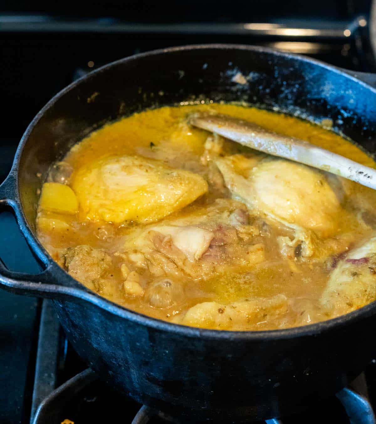 Curry chicken simmering in a Dutch oven on the stovetop.